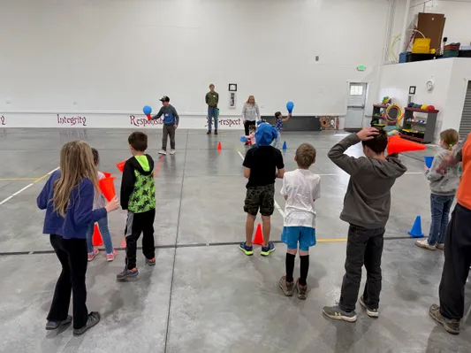 Youth lined up for a cone game activity in the gym with character values on the wall