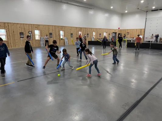 Youth playing floor hockey with foam sticks in the gym