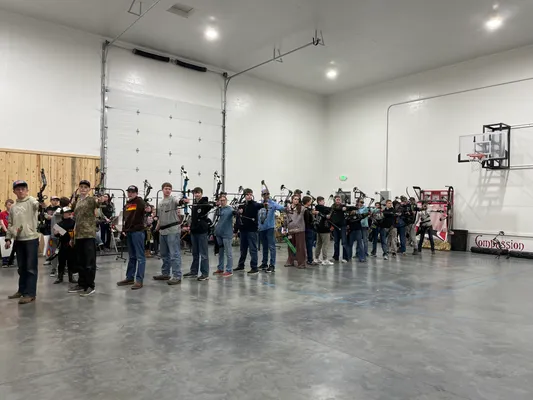 Full line of youth archers aiming at targets in the gym
